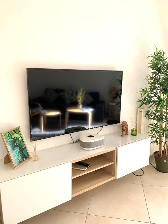 - un centre de divertissement blanc avec une grande télévision dans l'établissement Havre de paix moderne et spacieux, Évry-Courcouronnes