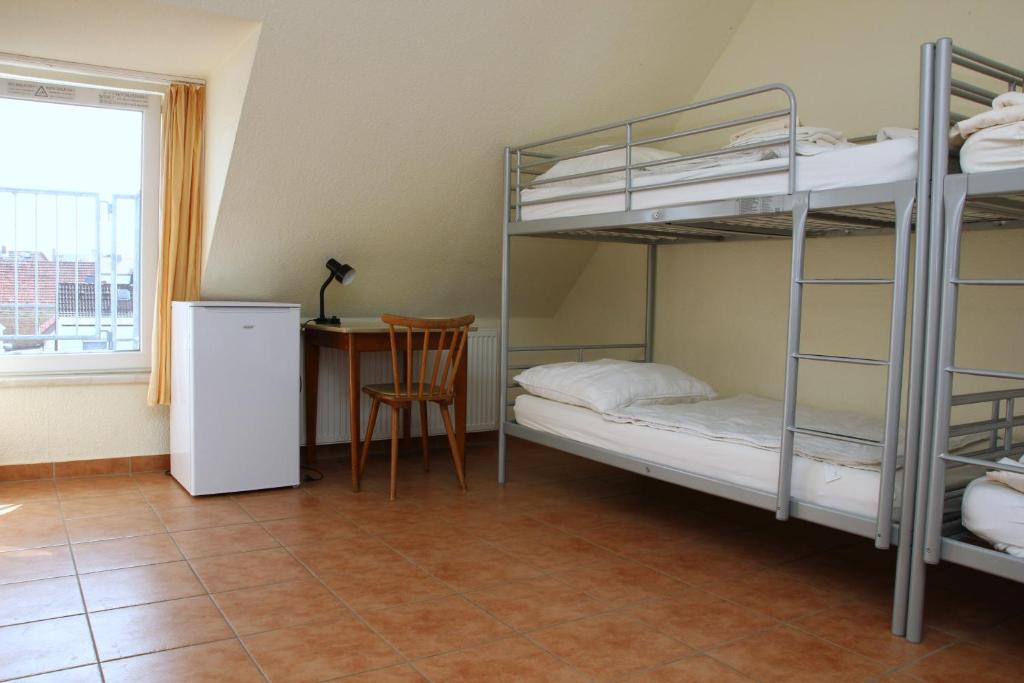 Zimmer mit 2 Etagenbetten und einem Tisch mit einem Fenster in der Unterkunft Wanderlust Hostel in Flörsheim