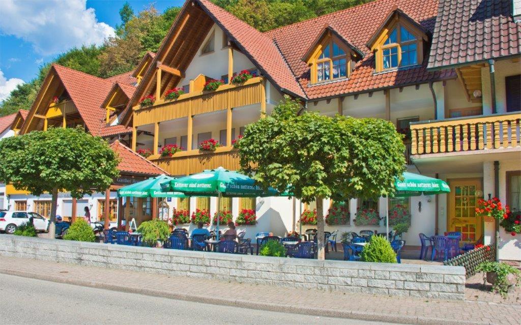 a building with tables and chairs and umbrellas at Hotel Walkenstein in Oberwolfach