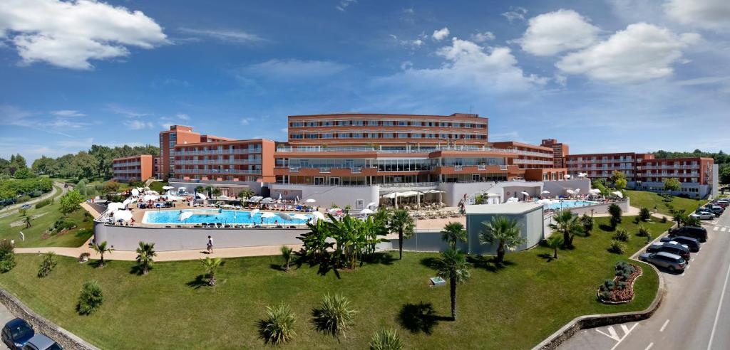 a large building with a swimming pool next to a road at Hotel Albatros Plava Laguna in Poreč