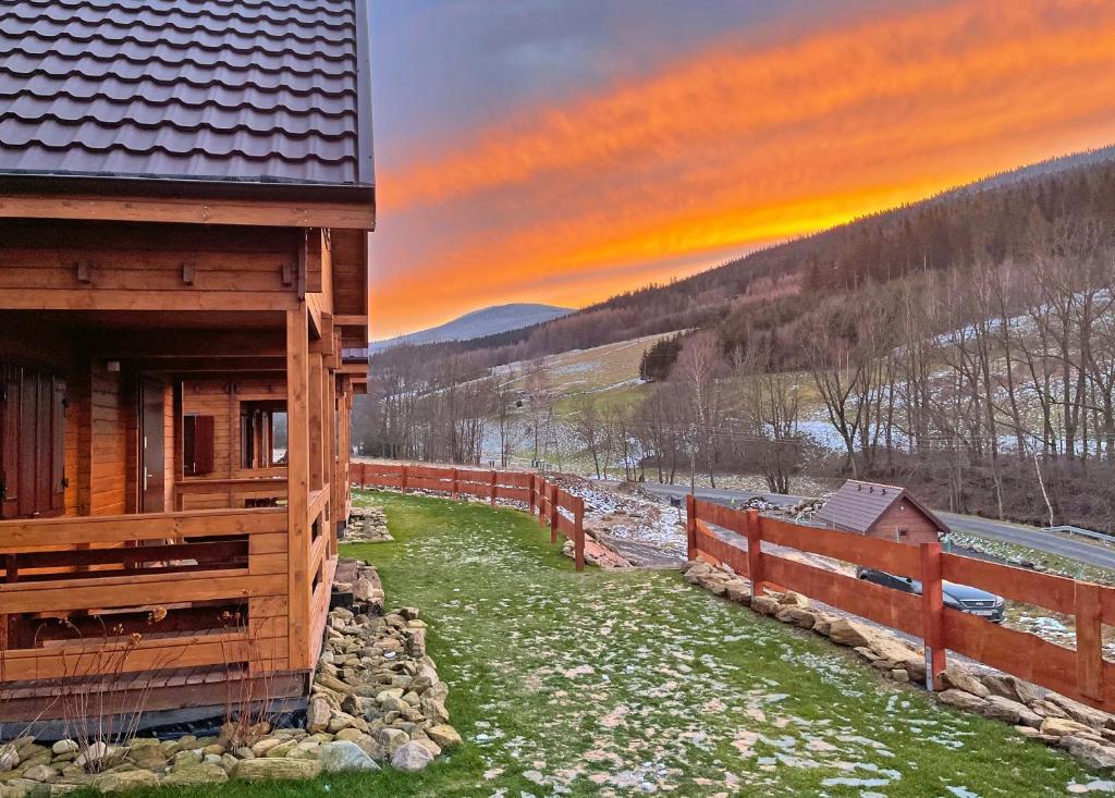 un bâtiment en bois avec une clôture à côté d'un champ dans l'établissement Chata Lisa, à Stronie Śląskie