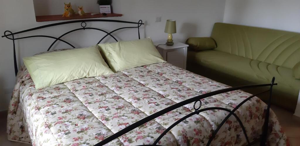 a bed with a quilt and a couch in a bedroom at Casale Del Borgo in Hermada