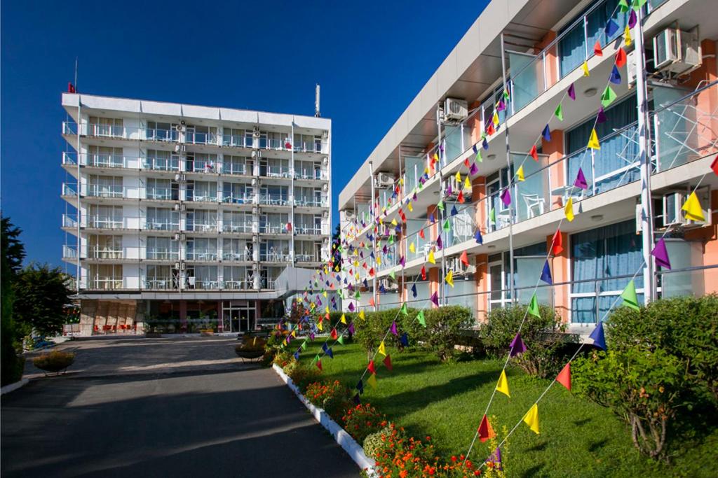 a building with flags and flowers in front of it at Hotel Coop - Kiten in Kiten