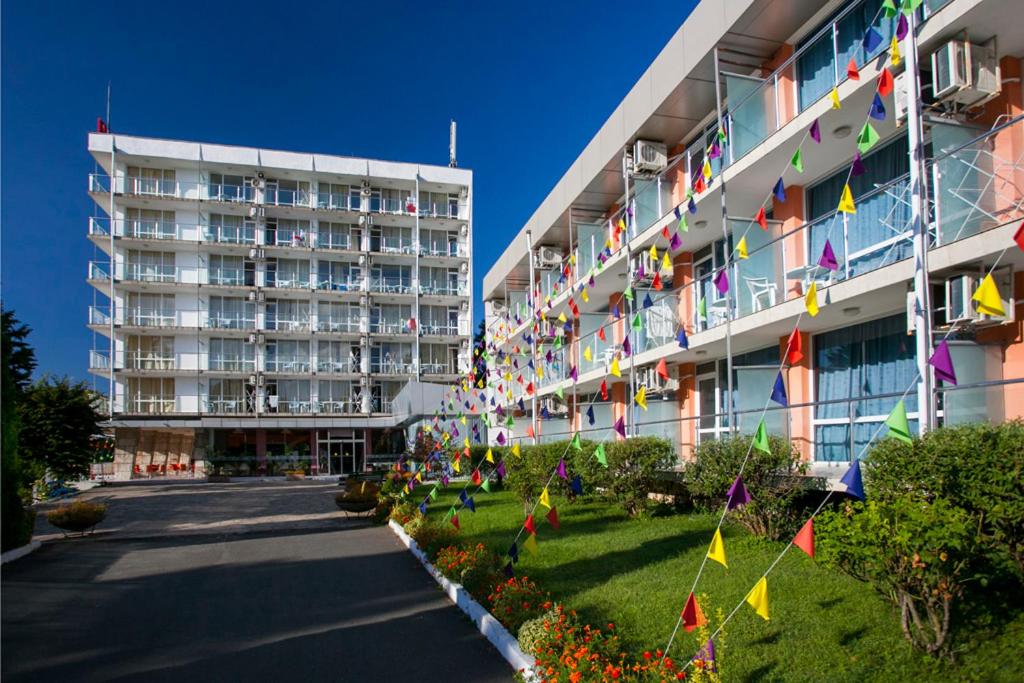 un edificio con banderas y flores delante de él en Hotel Coop - Kiten, en Kiten