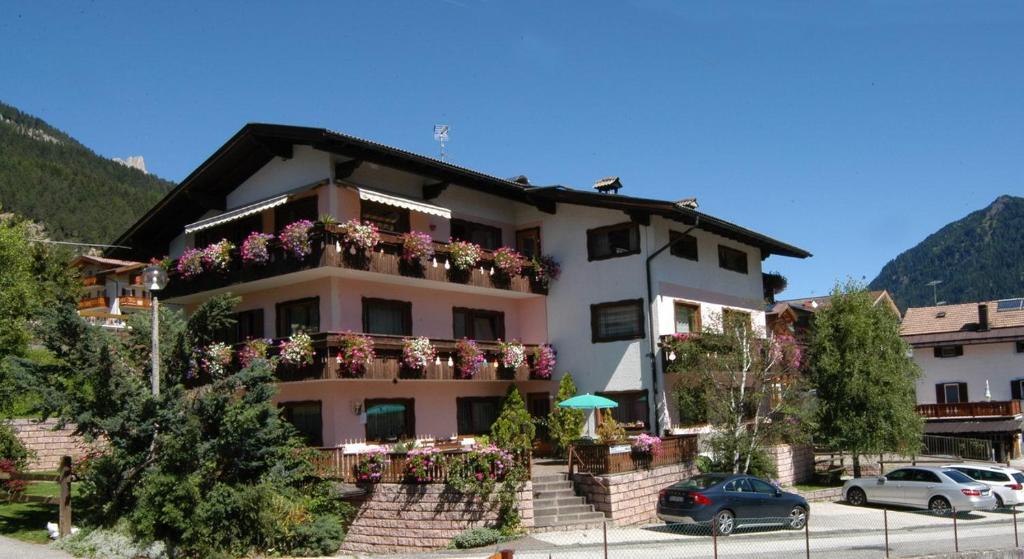 un bâtiment avec des fleurs sur ses balcons dans l'établissement Residence Weiss, à Vigo di Fassa