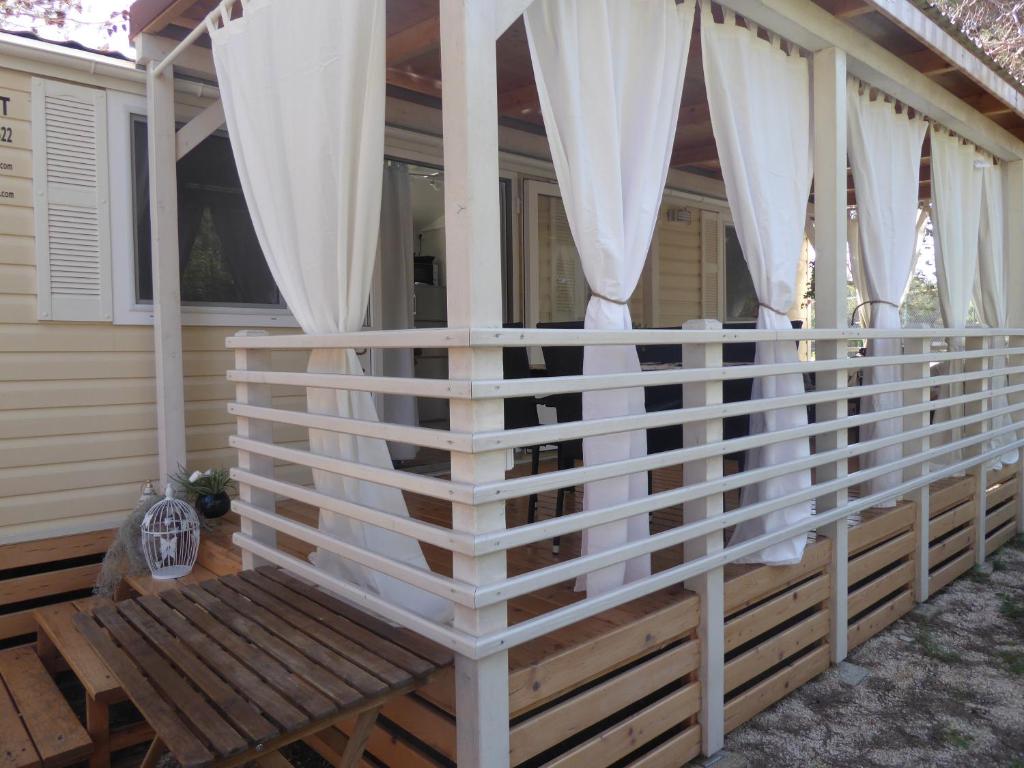 a porch with white curtains and a wooden bench at Adriatic Blue Coast Mobile Home in Jezera