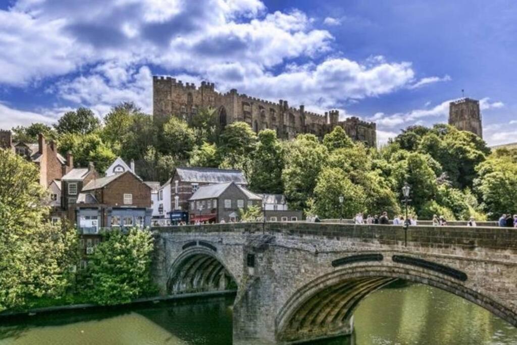 a bridge over a river with a castle in the background at Spacious Durham City Centre Riverside Apartment in Durham