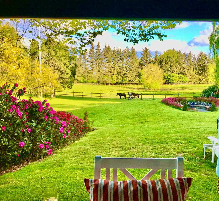 un banco blanco sentado en un parque con flores en The Swiss hut 30 minutes from Copenhagen, en Kvistgård