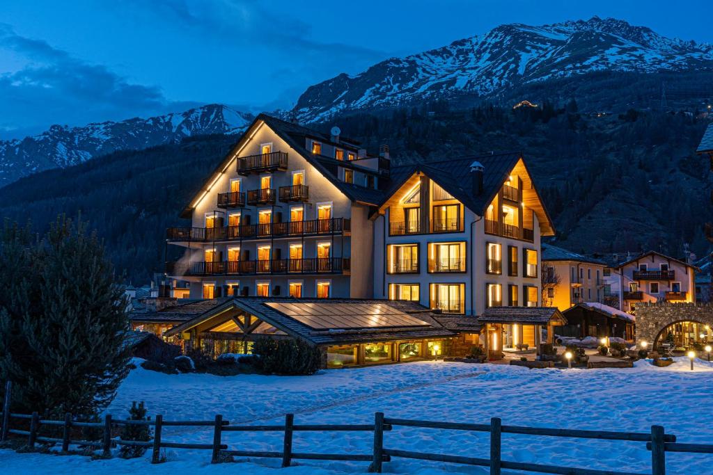 a large building in the snow at night at Hotel Sant'Orso - Mountain Lodge & Spa in Cogne
