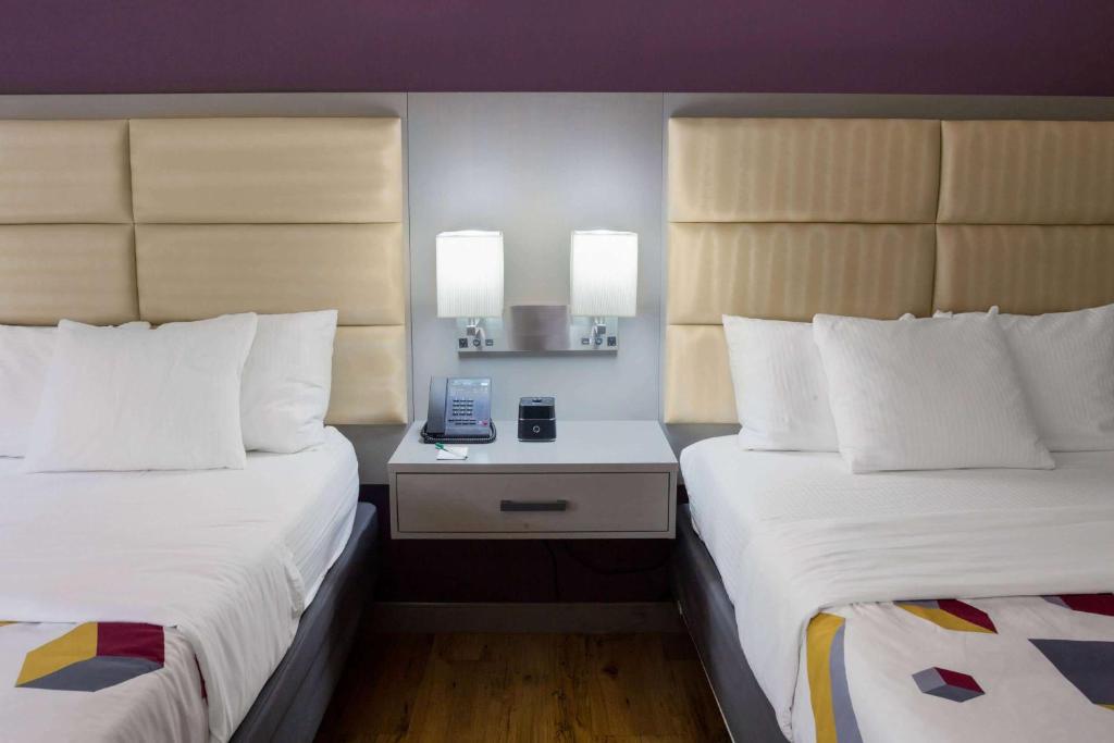 a hotel room with two beds and a phone on a night stand at La Quinta by Wyndham Mobile - Daphne in Daphne