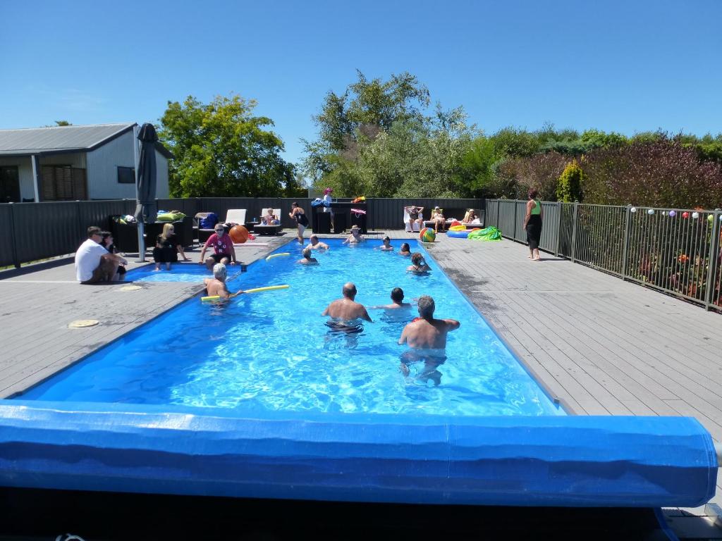 a group of people playing in a swimming pool at Cottages On St Andrews in Havelock North