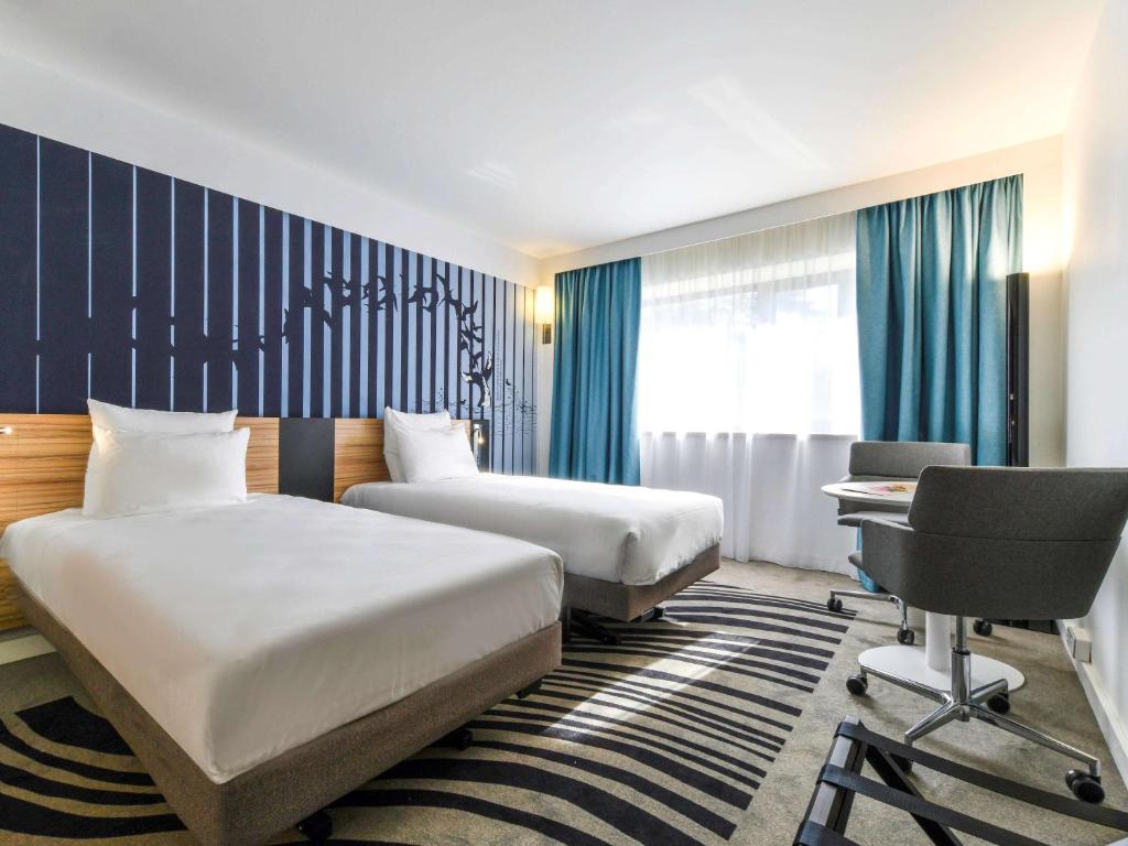 Habitación de hotel con 2 camas y escritorio en Novotel La Rochelle Centre, en La Rochelle