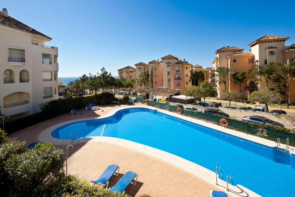 una gran piscina con tumbonas y edificios en Hacienda Playa Elviria Marbella, en Marbella