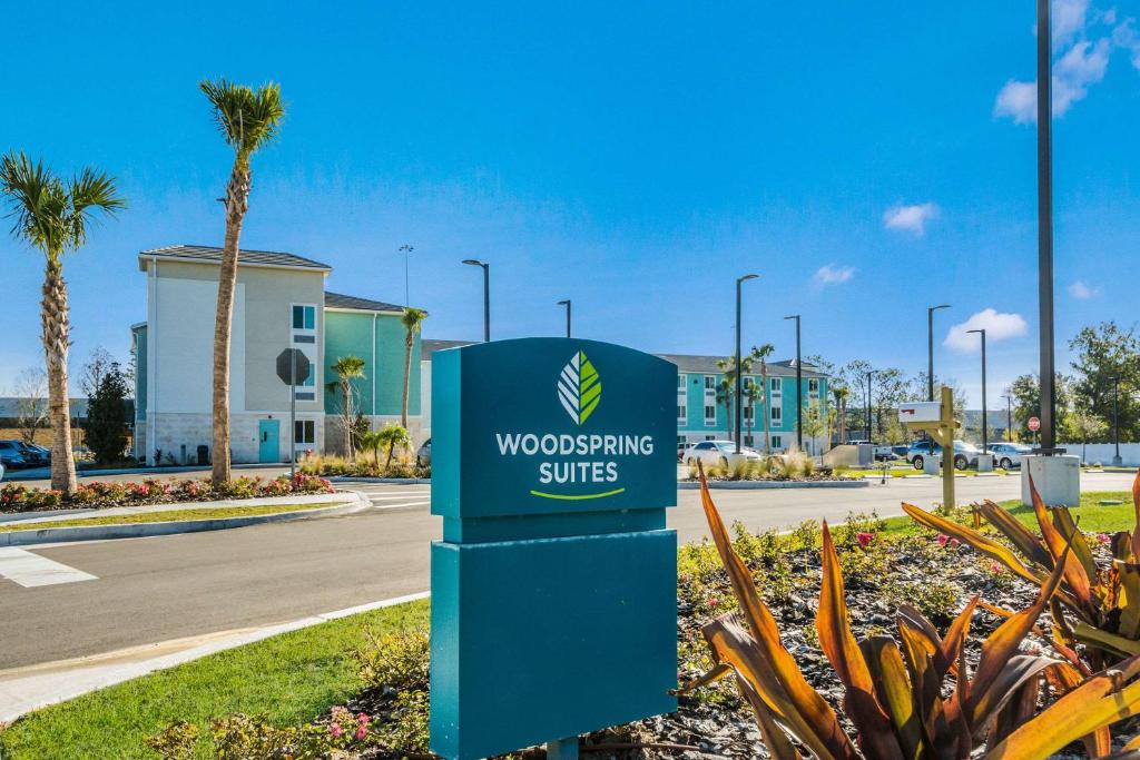 WoodSpring Suites Bradenton في برادنتون: علامة لاجنحة خشبية في موقف للسيارات