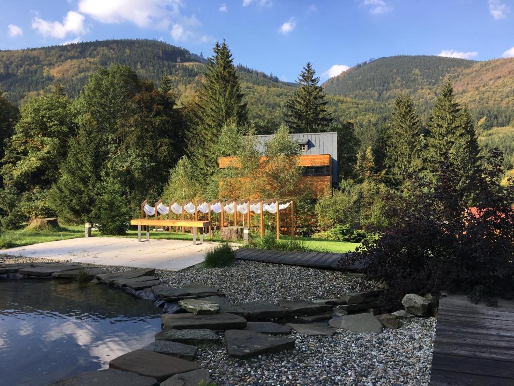 ein Gebäude mit einer Bank neben einem Fluss in der Unterkunft Hotel & Garden U Holubů in Čeladná