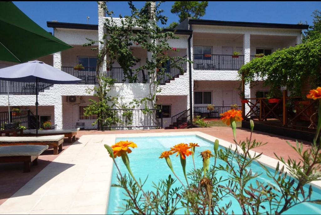 a swimming pool with flowers in front of a building at Mediterráneo Suites in Puerto Iguazú