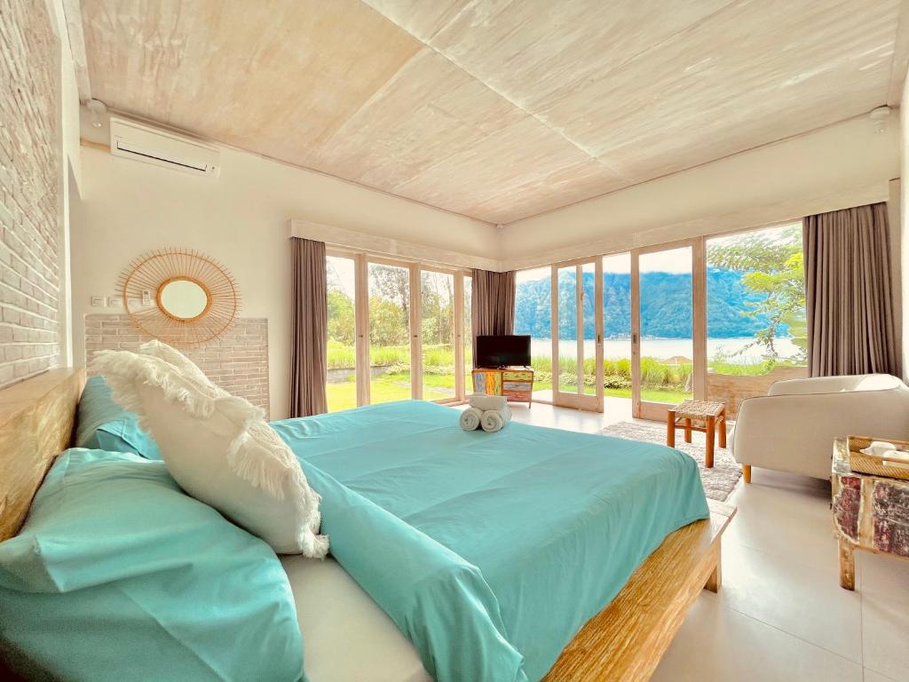 a bedroom with a blue bed and a large window at Volcano Terrace Bali in Kintamani