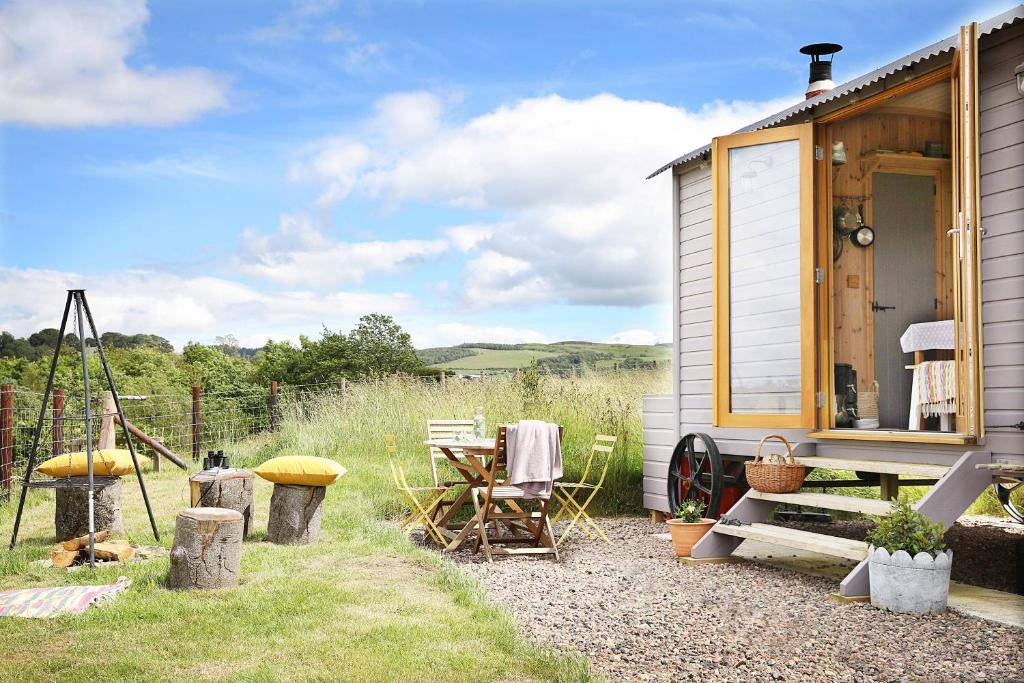 una casa pequeña con mesa y sillas al aire libre en Westfield House Farm, en Rothbury