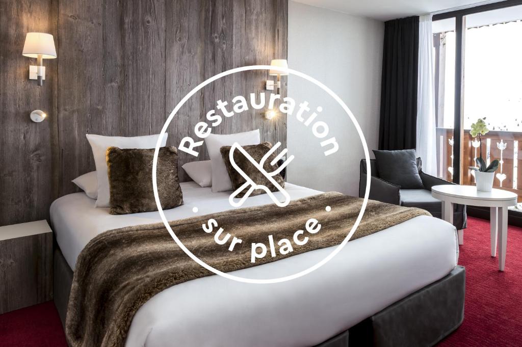 a hotel room with a bed with a sign on it at Le Pic Blanc in L'Alpe-d'Huez