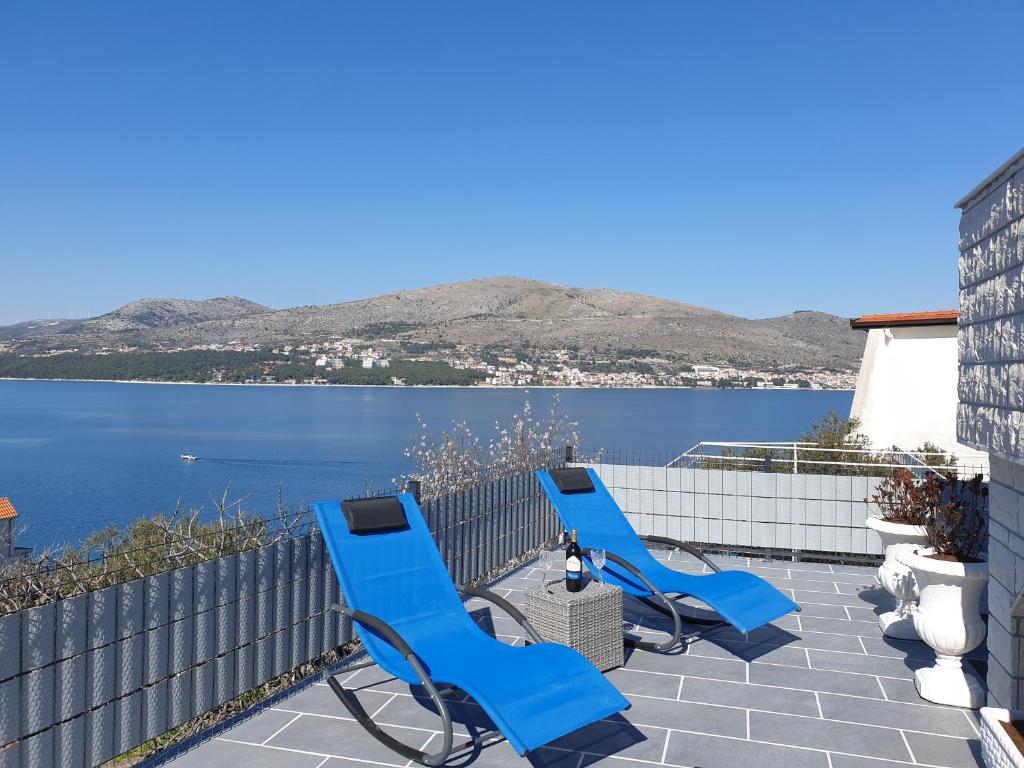 três cadeiras azuis sentadas num pátio com vista para a água em Villa Sandrina em Okrug Donji