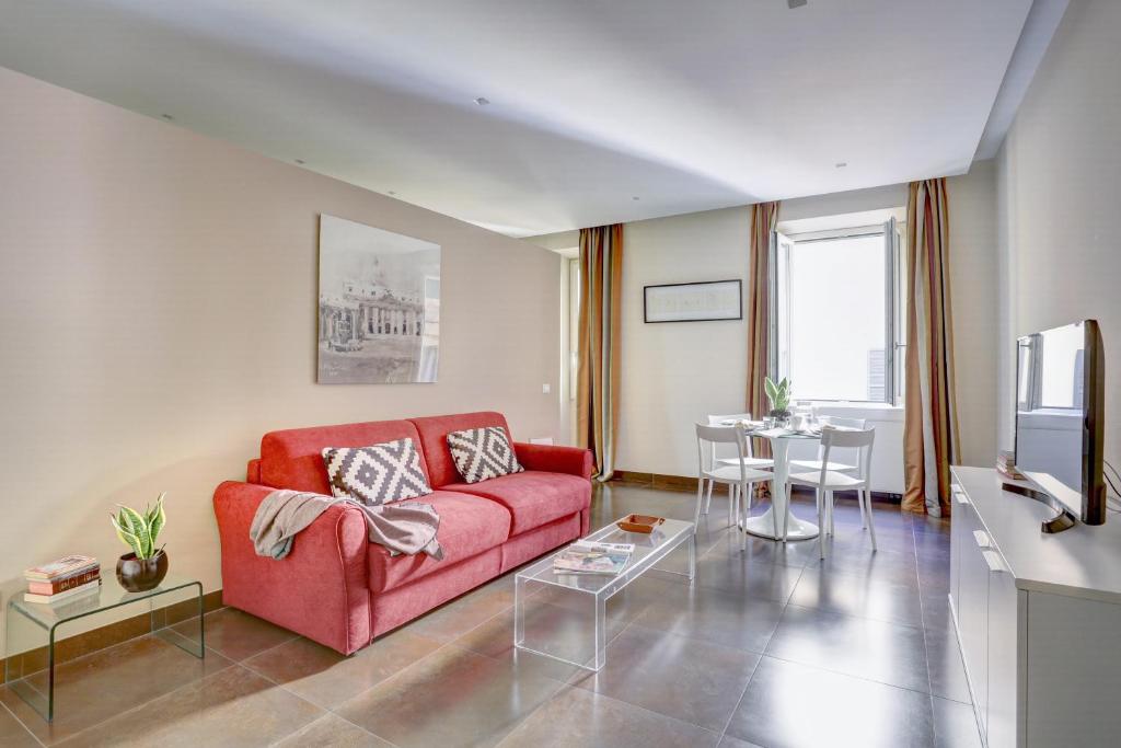 ein Wohnzimmer mit einem roten Sofa und einem Tisch in der Unterkunft Colosseo Gardens - My Extra Home in Rom