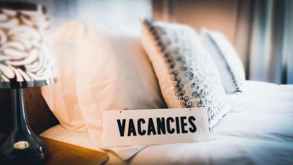 a sign sitting on a bed with pillows on it at Sandyhill Guest House in Pembrokeshire