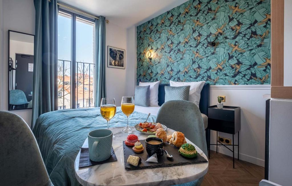 ein Hotelzimmer mit einem Bett und einem Tisch mit Speisen und Wein in der Unterkunft Mijo's Appartements Hôtel in Fontenay-sous-Bois