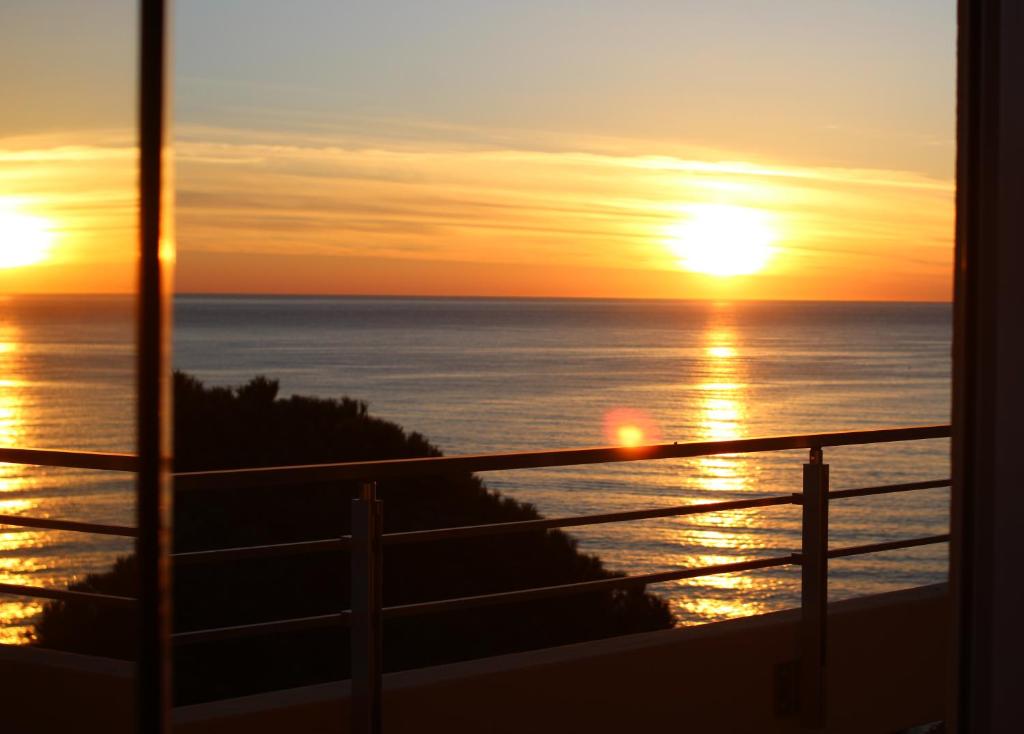 einen Sonnenuntergang über dem Meer vom Balkon aus in der Unterkunft Hôtel Alexandra in Roquebrune-Cap-Martin