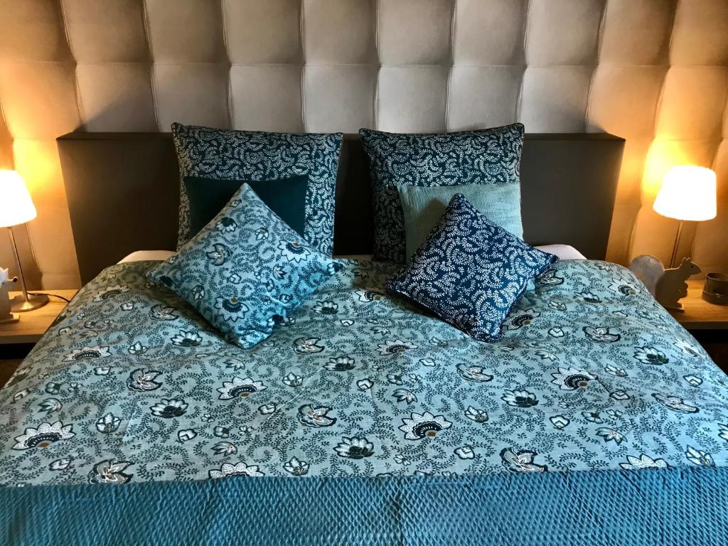 uma cama com um cobertor azul e almofadas em Le Chalet de Marguerite em Francorchamps