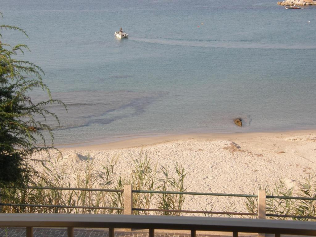 vistas a una playa con un barco en el agua en Isola Rossa Appartamenti Bellavista en Isola Rossa