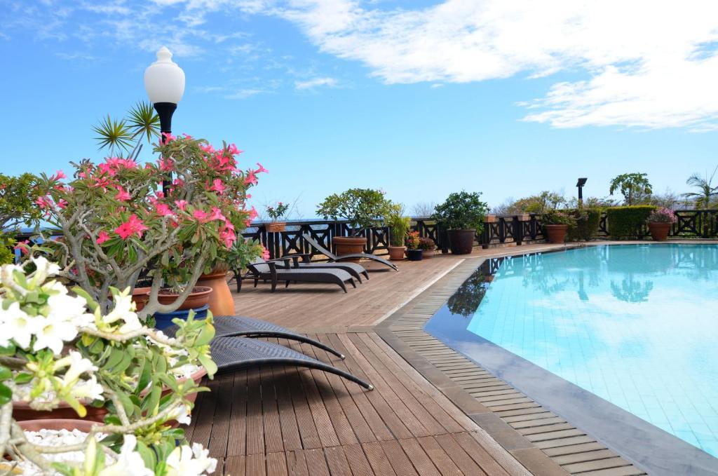 un patio con una piscina con flores y mesas en Cases Couleurs en Saint-Leu