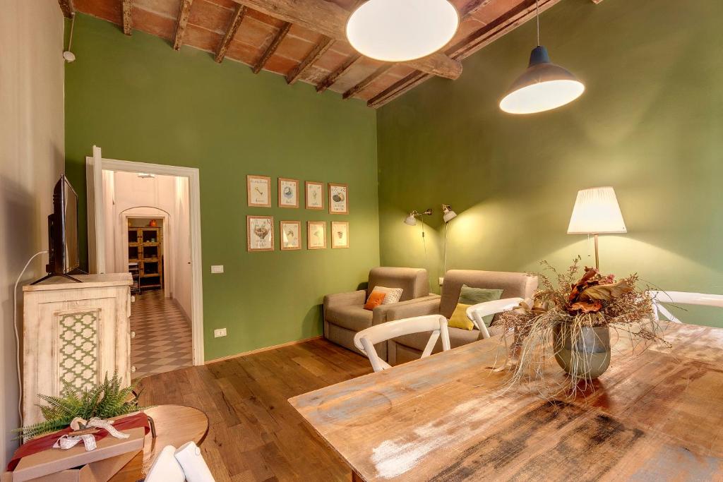 - un salon avec des murs verts et une table en bois dans l'établissement Mamo Florence - GM Apartment, à Florence