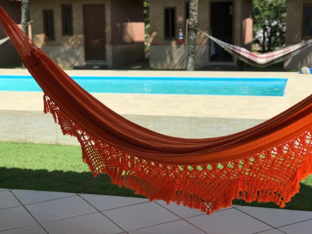an orange hammock in front of a pool at Pousada Nativo's in Nova Almeida