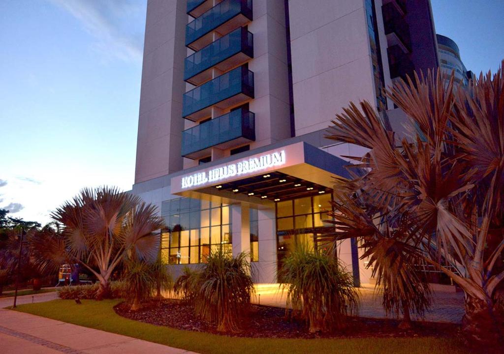 a hotel building with palm trees in front of it at Hplus Premium Palmas in Palmas