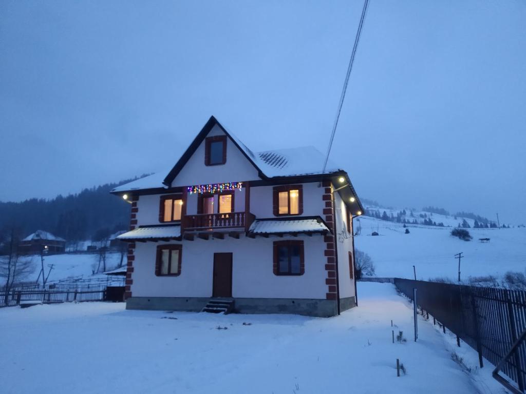 Una casa con luces en la nieve en Гірська Домівка, en Volosyanka