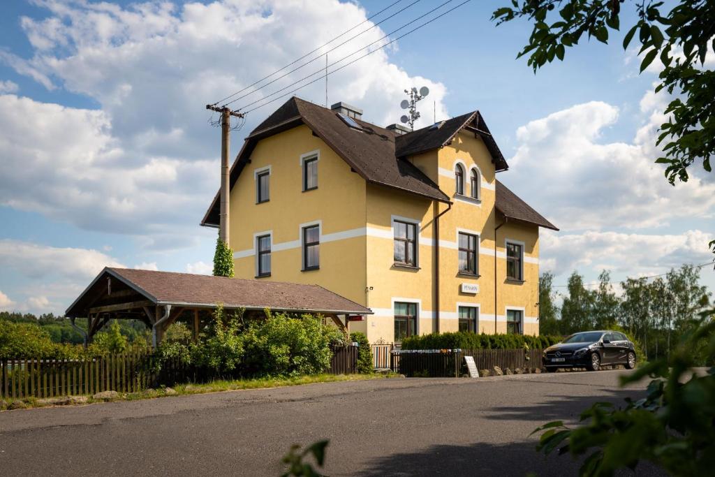 a large yellow house with a gambrel roof at Pension Vetrny Vrch in Ostrov
