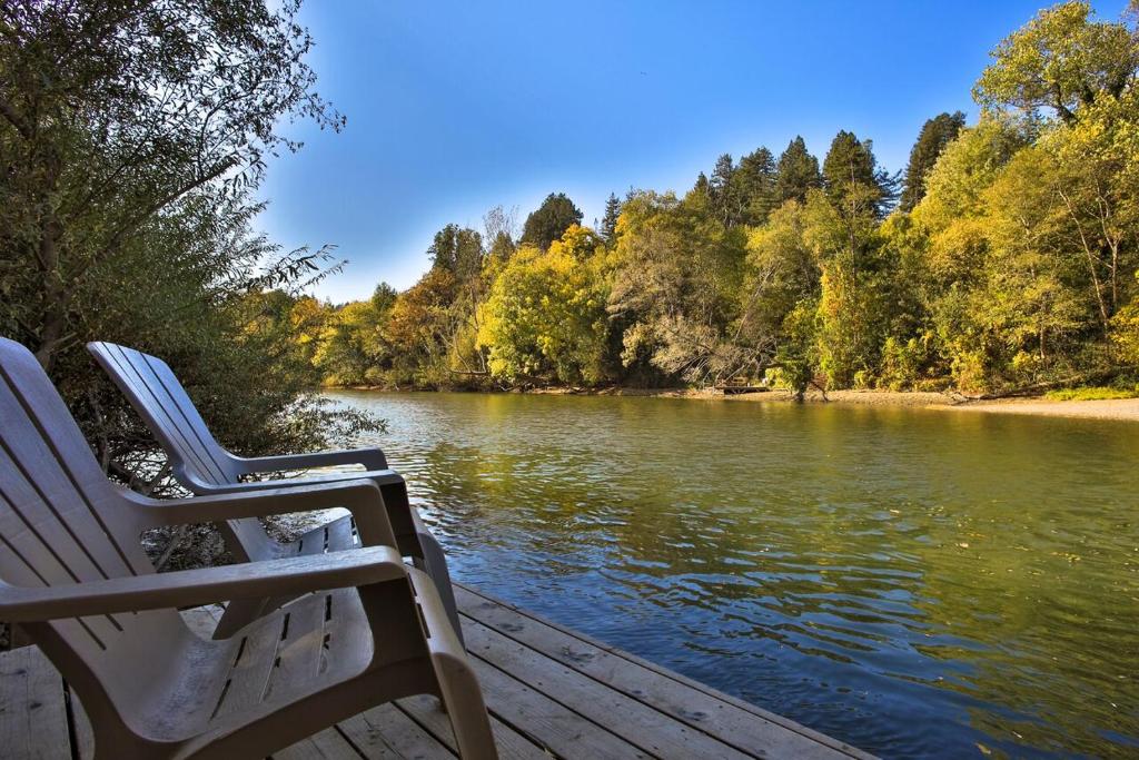 two chairs sitting on a dock next to a river at Lily Pad - Hot Tub! Private Dock! BBQ! Game Room! Walk to Town!! Fast WiFi!! Dog Friendly! in Guerneville