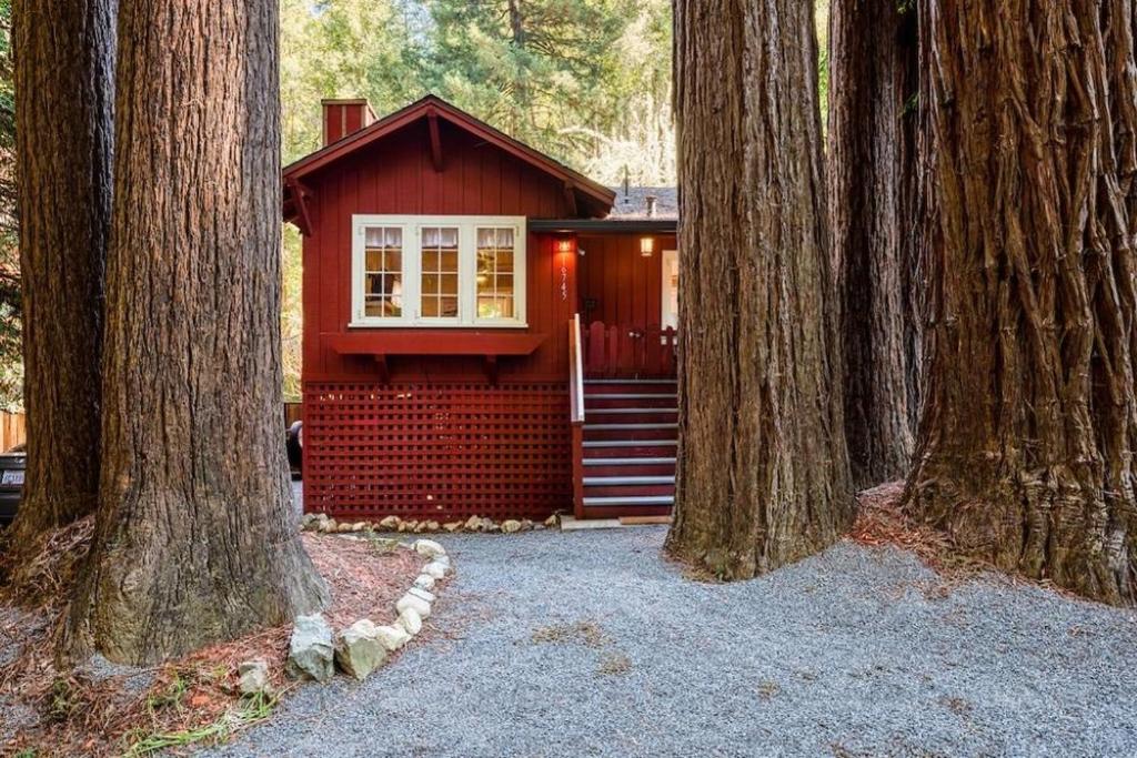 a small red house sitting between two trees at Redwood Retreat! Redwoods! Walk to River!! Hot Tub!! BBQ! Central Air!! in Guerneville
