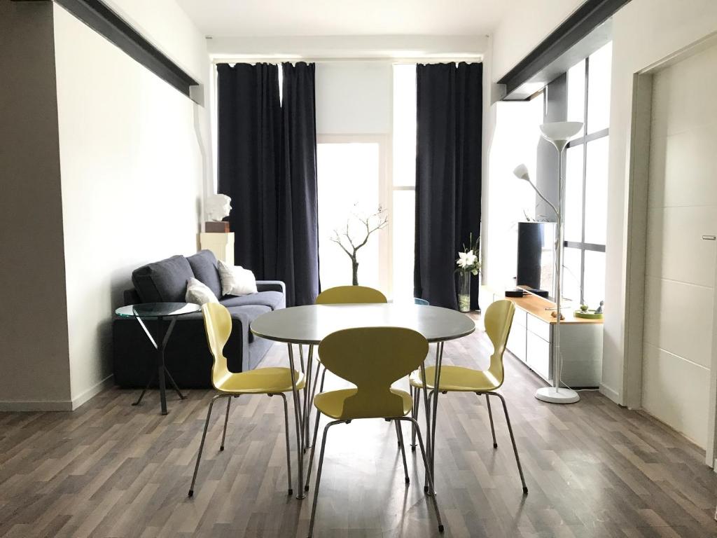 - un salon avec une table et des chaises jaunes dans l'établissement B@Home Apartments, à Sanem