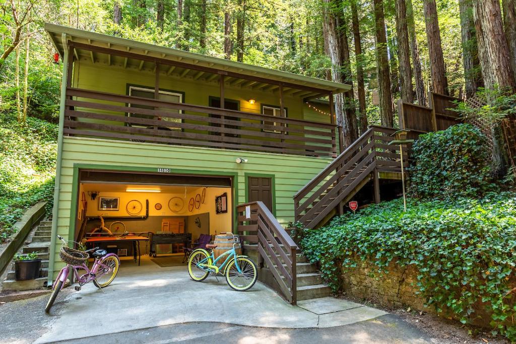 una casa verde con dos bicicletas estacionadas frente a ella en Vino Velo Retreat! Redwoods! Hot Tub!! Fire Table!! BBQ!! Game Room!! Fast WiFi!! Dog Friendly!!, en Guerneville
