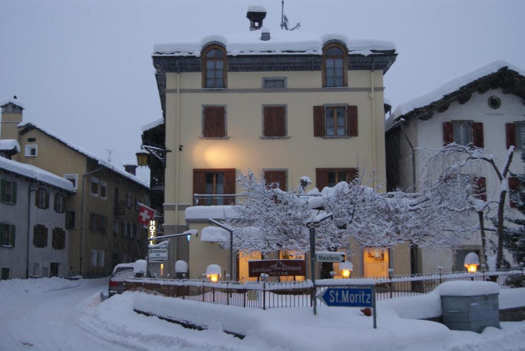 un edificio con nieve en el suelo delante de él en Albergo Piz Cam en Vicosoprano