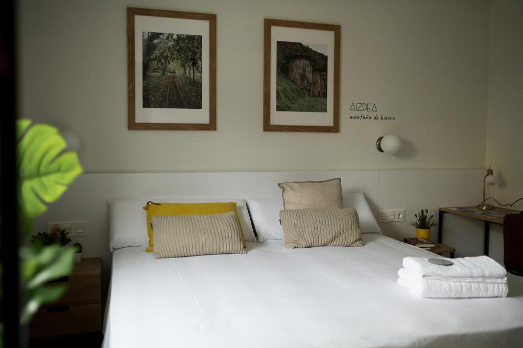 a bedroom with a white bed with two pillows at HOTEL ORDIZIA in Villafranca de Ordizia