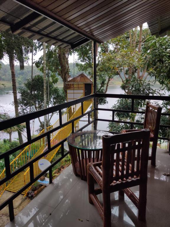 a balcony with a glass table and two chairs at 7 Heaven Resorts in Ambalavayal