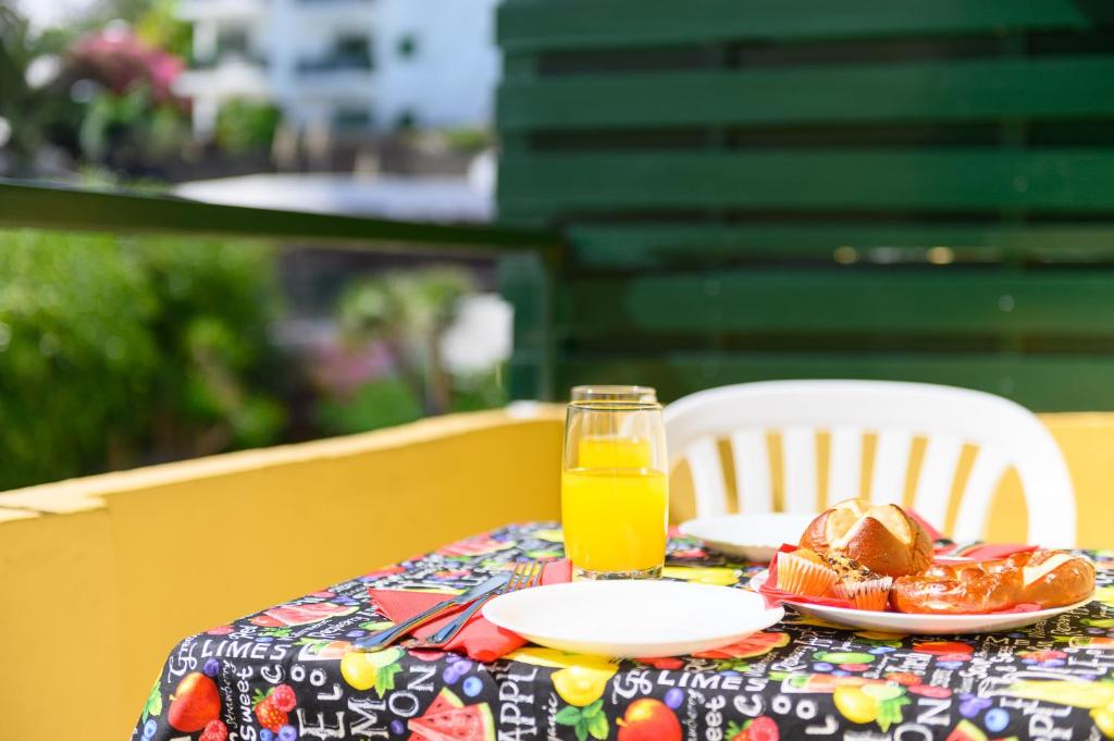 una mesa con un plato de comida y un vaso de zumo de naranja en Caroni, en Playa del Inglés
