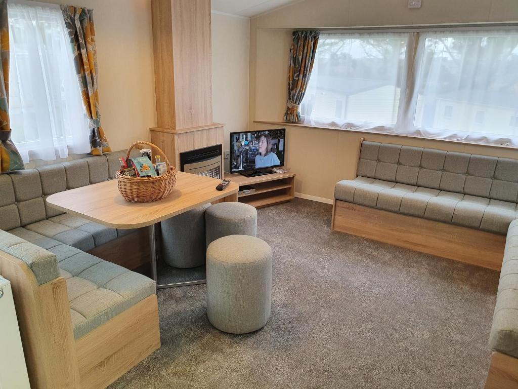 een woonkamer met een bank en een tafel bij Cozy 3 bedroom Caravan, Sleeps 8, at Parkdean Newquay Holiday Park in Newquay