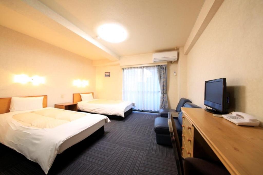 a hotel room with two beds and a flat screen tv at Monthly Mansion Tokyo West 21 - Vacation STAY 10881 in Fuchu