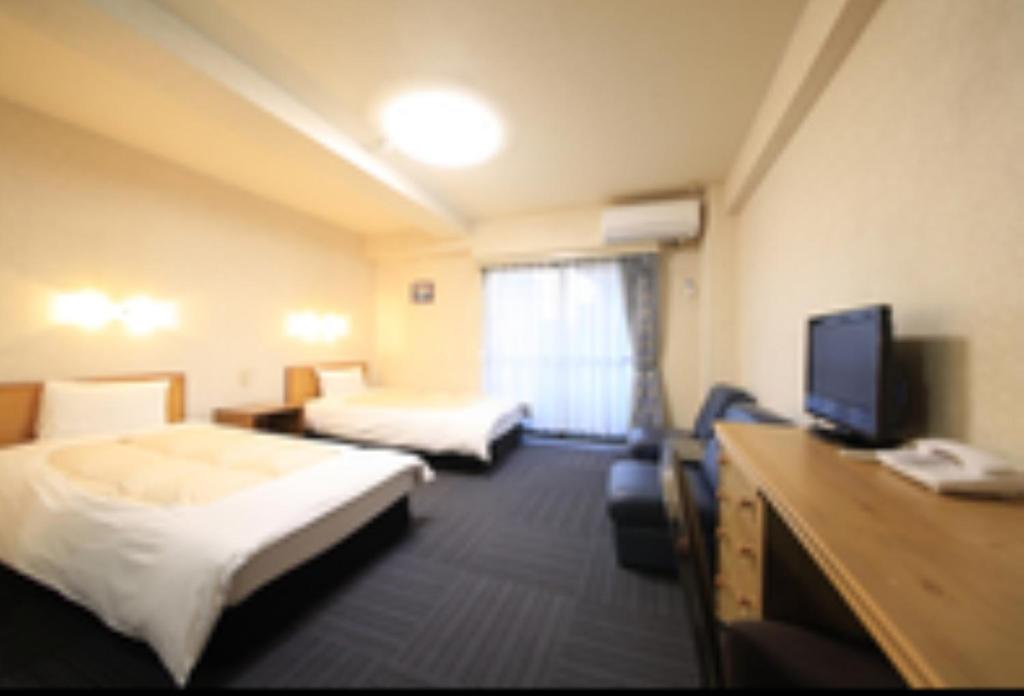 a hotel room with two beds and a flat screen tv at Monthly Mansion Tokyo West 21 - Vacation STAY 10889 in Fuchu