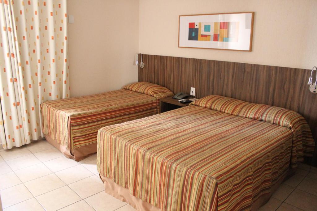 a hotel room with two beds and a picture on the wall at Hotel Riviera in Sao Jose do Rio Preto