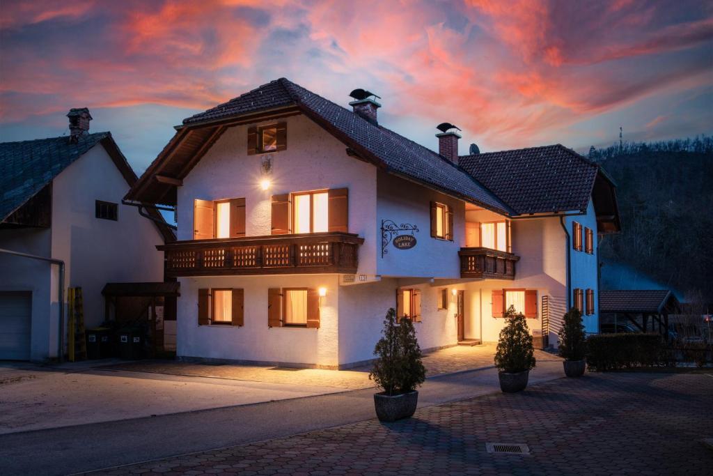 een groot wit huis met een zonsondergang op de achtergrond bij Holiday Lake in Bled