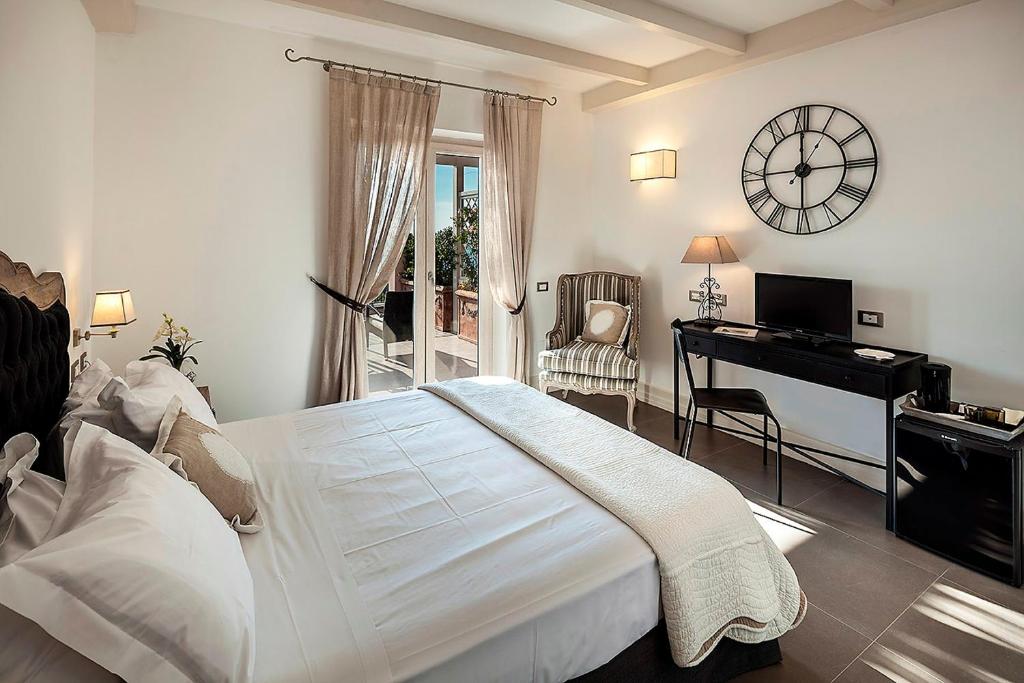a bedroom with a bed and a desk and a clock at Tenuta Del Poggio Antico in Ischia
